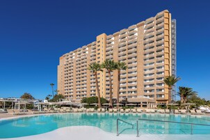 Un gran hotel con piscina, varias plantas y palmeras.