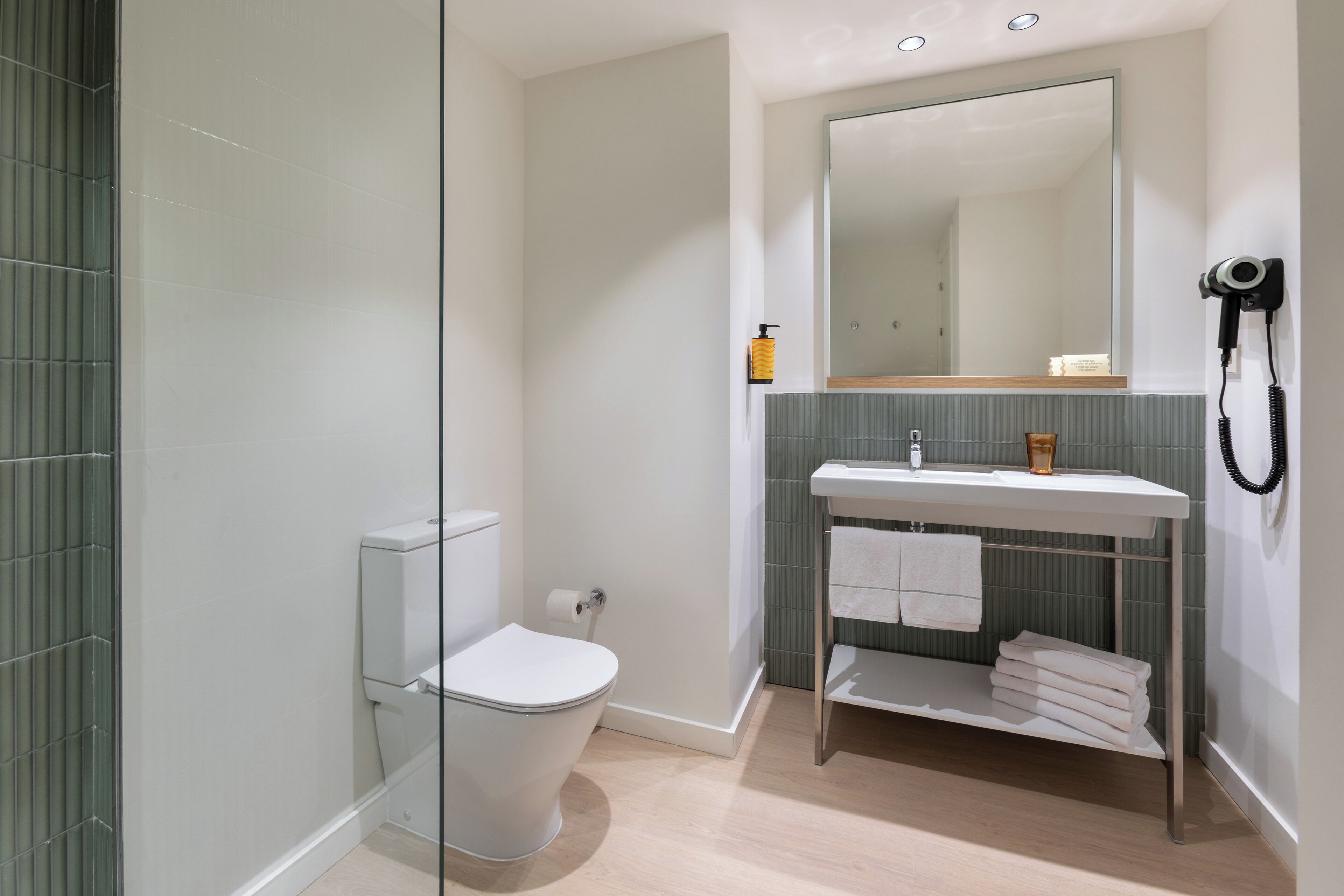A modern bathroom with a toilet, sink, and mirror.