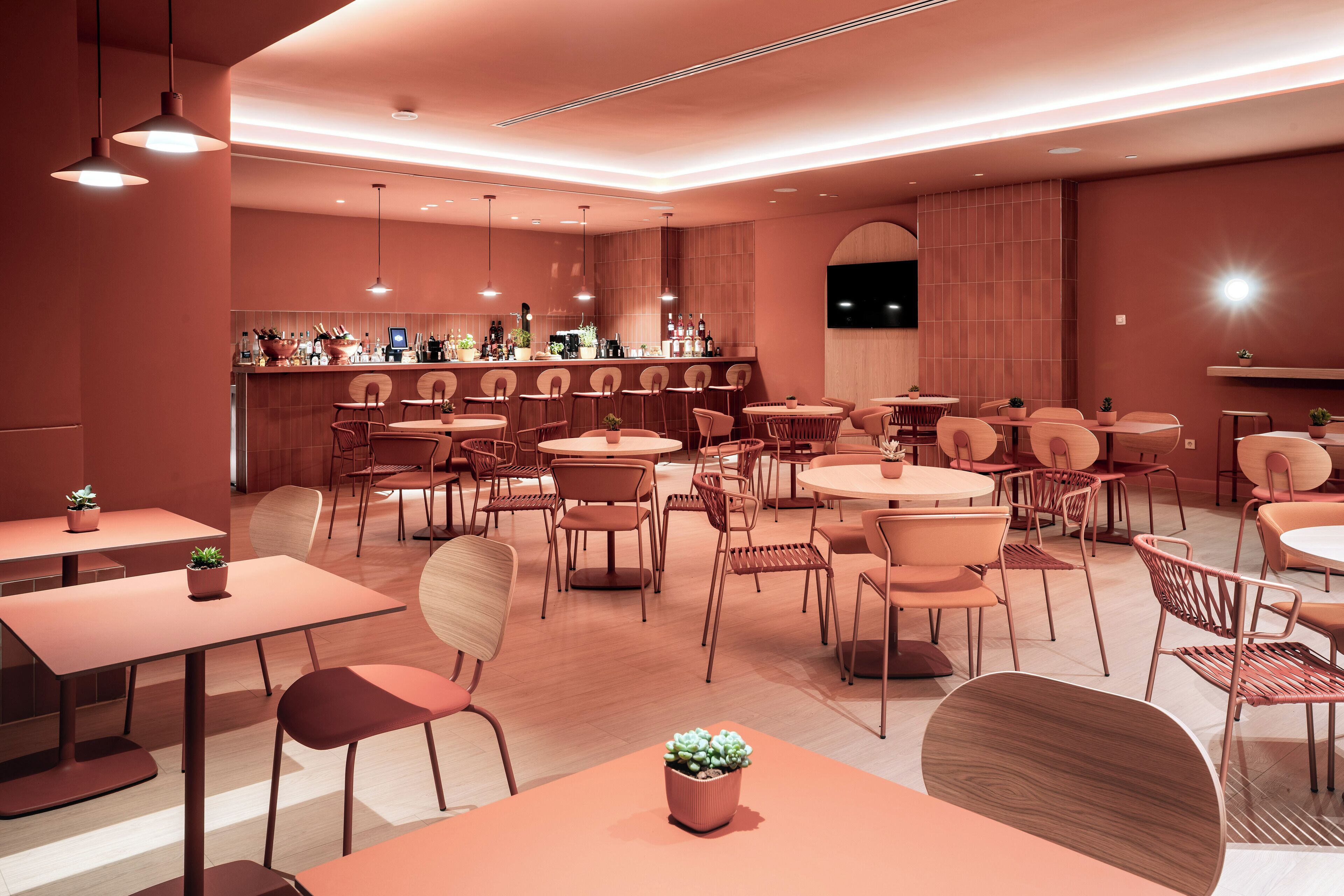 Un intérieur moderne doté de plusieurs espaces de détente, d’un bar et d’un écran de télévision.