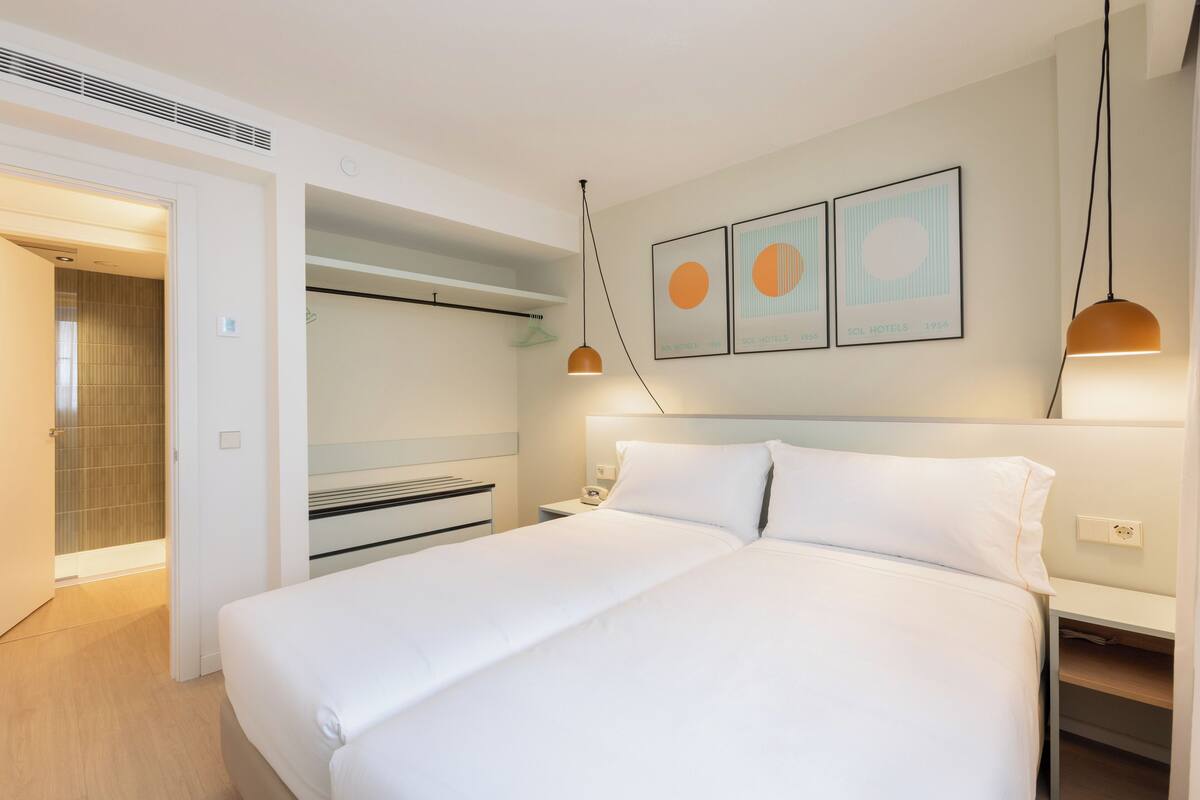 Une chambre d’hôtel moderne avec un grand lit, des tables de chevet, une armoire et un espace douche.