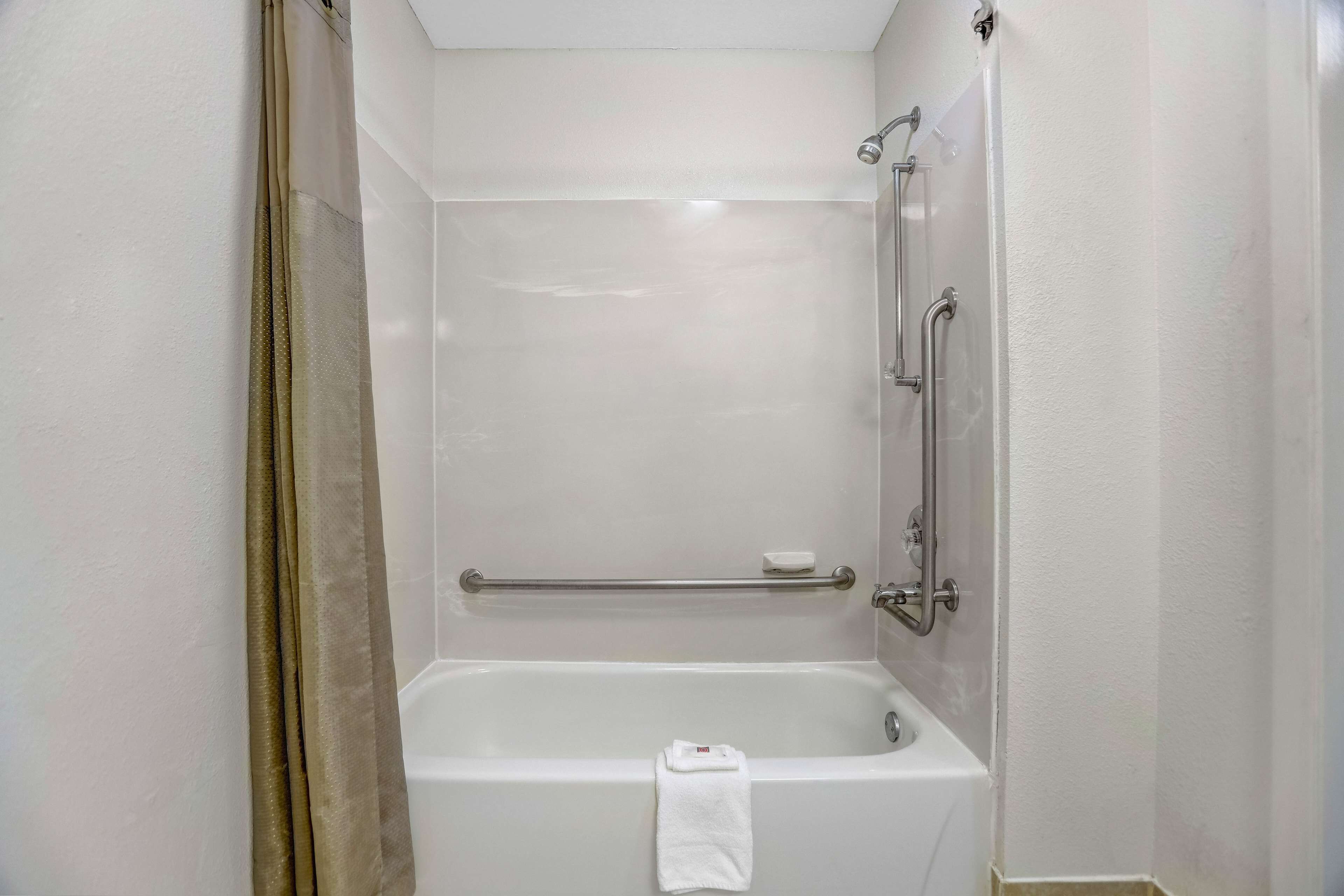 A bathroom with a bathtub, a shower, and a grab bar.