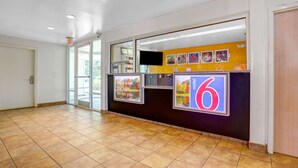 A hotel reception area with a tiled floor, a reception desk, and a large number '6' sign. - Motel 6 Raleigh, NC - North (Raleigh)