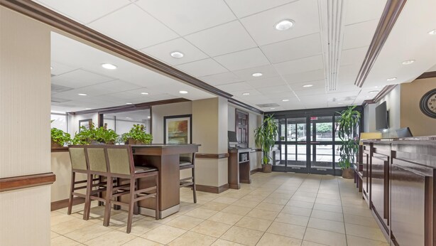 A spacious lobby with a reception desk, seating area, and potted plants. - Best Western Dulles Airport Inn (Sterling)