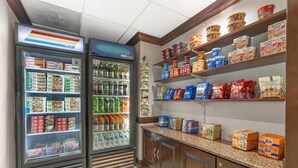 A refrigerated display case with various food items and a shelf stocked with snacks and packaged goods. - Best Western Dulles Airport Inn (Sterling)