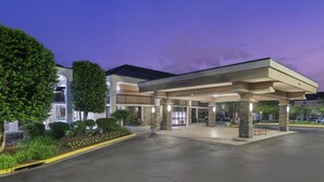 A hotel entrance with a covered area, outdoor seating, and a parking lot. - Best Western Dulles Airport Inn (Sterling)
