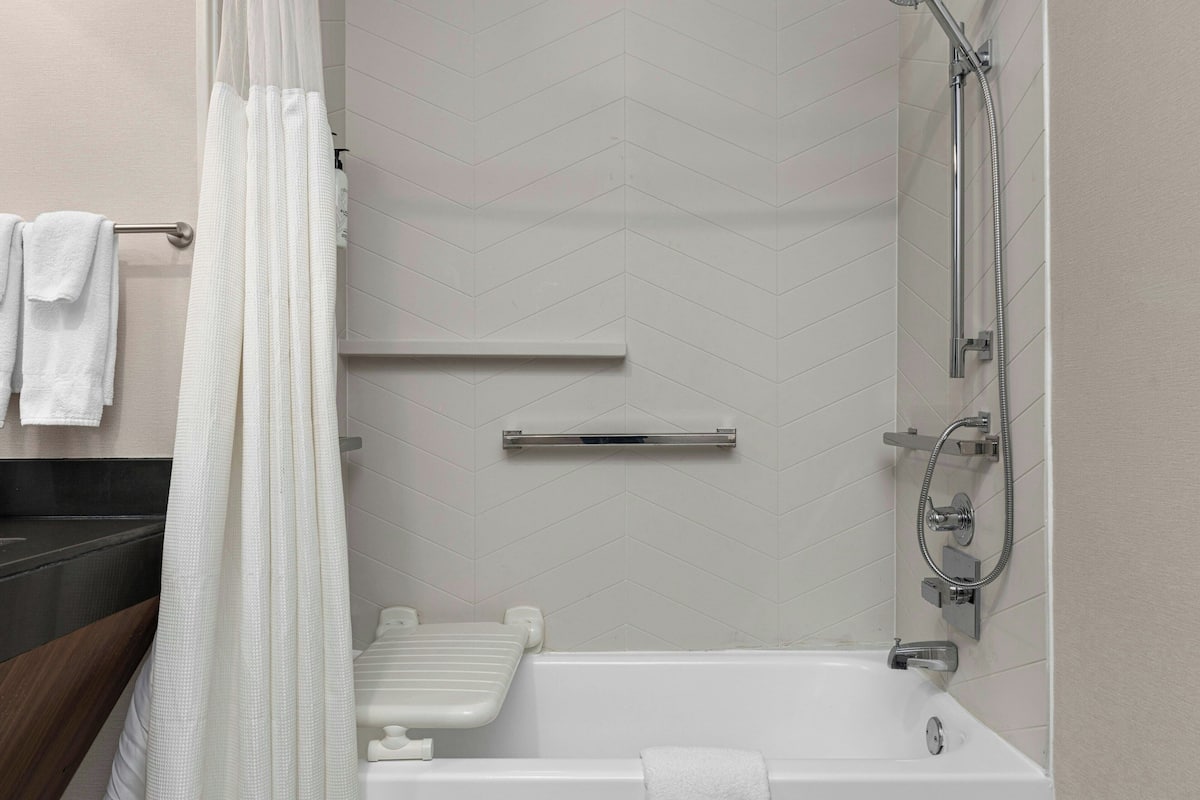A modern bathroom with a bathtub, shower, and a towel rack.