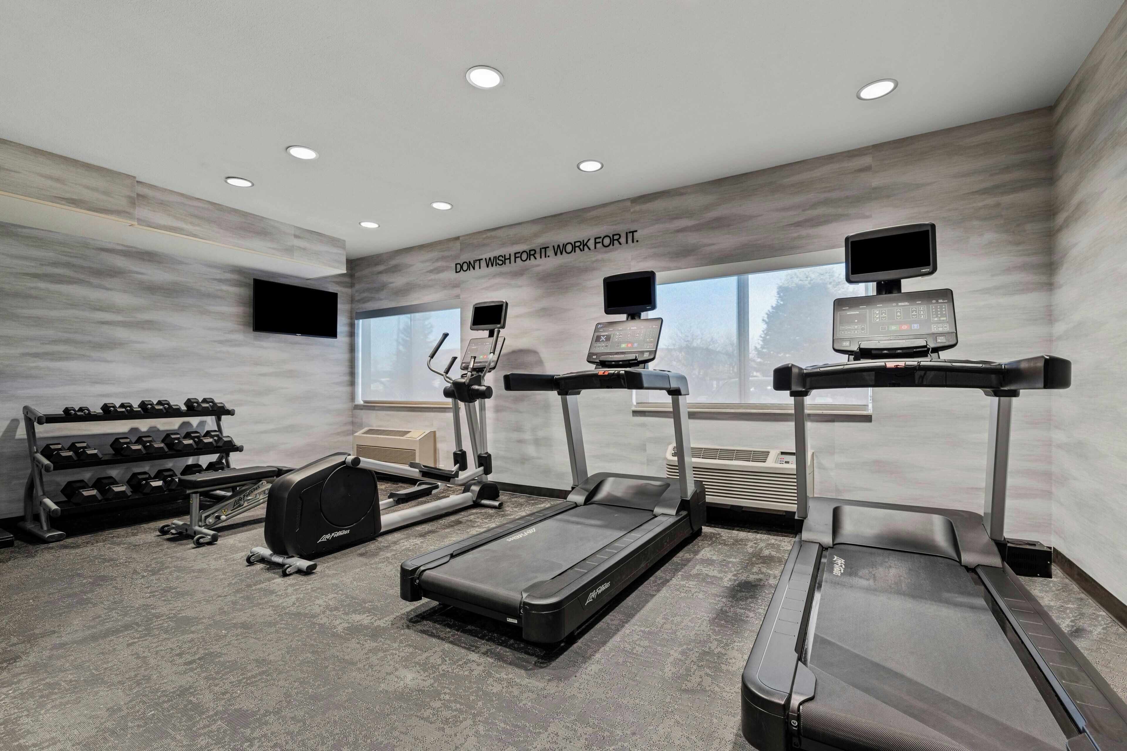 A modern gym with treadmills, a stationary bike, and a weight rack.