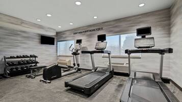 A modern gym with treadmills, a stationary bike, and a weight rack.