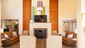 A lobby with two sofas, a fireplace, and a television mounted on the wall. - Comfort Suites Baton Rouge South I-10 (Baton Rouge)