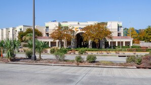 A multi-story building with a central entrance, surrounded by landscaped areas and palm trees. - Comfort Suites Baton Rouge South I-10 (Baton Rouge)