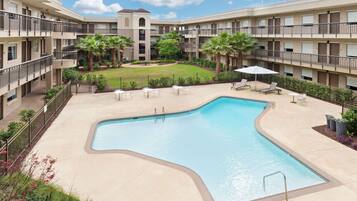 Relax by the rectangular pool surrounded by lounge chairs and umbrellas.