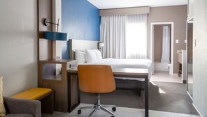 A hotel room with a bed, a desk, a chair, a small table, and a bathroom visible through an open door. - Comfort Suites Baton Rouge South I-10 (Baton Rouge)