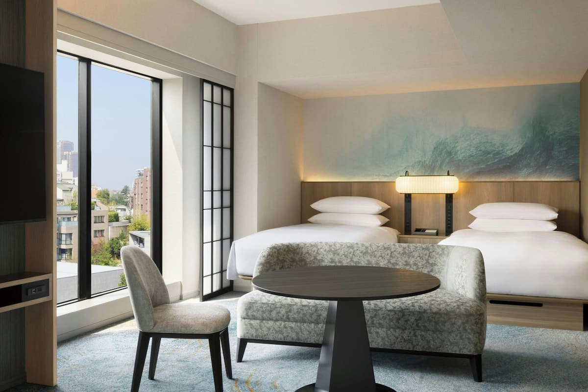 A hotel room with a large bed, a desk, a chair, a TV, and a city view.