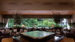 A spacious lobby with a central pool, comfortable seating, and large windows offering a view of lush greenery. - Sheraton Miyako Hotel Tokyo (Tokyo)