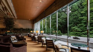 A spacious lobby with a high ceiling, large windows offering a view of a forest, and a variety of seating arrangements including sofas and chairs. - Sheraton Miyako Hotel Tokyo (Tokyo)