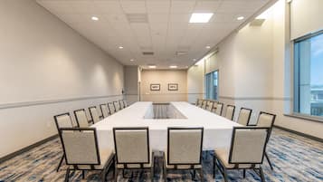 A conference room with a long table, chairs, and a carpeted floor.