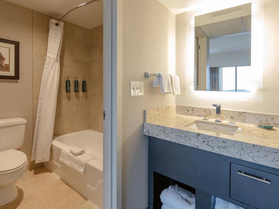 Un baño con bañera, inodoro y lavamanos con espejo.