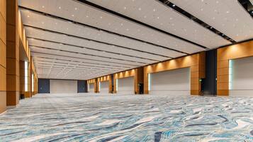 A spacious hall with a patterned carpet, multiple doors, and a high ceiling with recessed lighting.