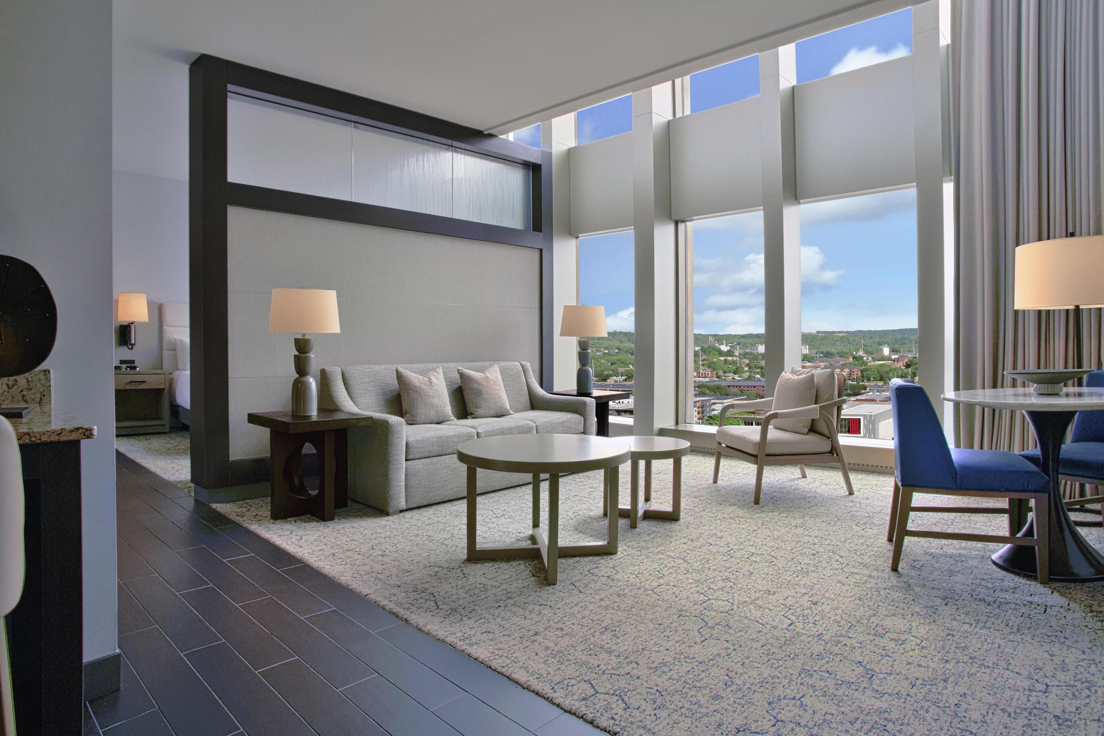 A modern living room with a sofa, two side tables, a coffee table, and a dining area with chairs.