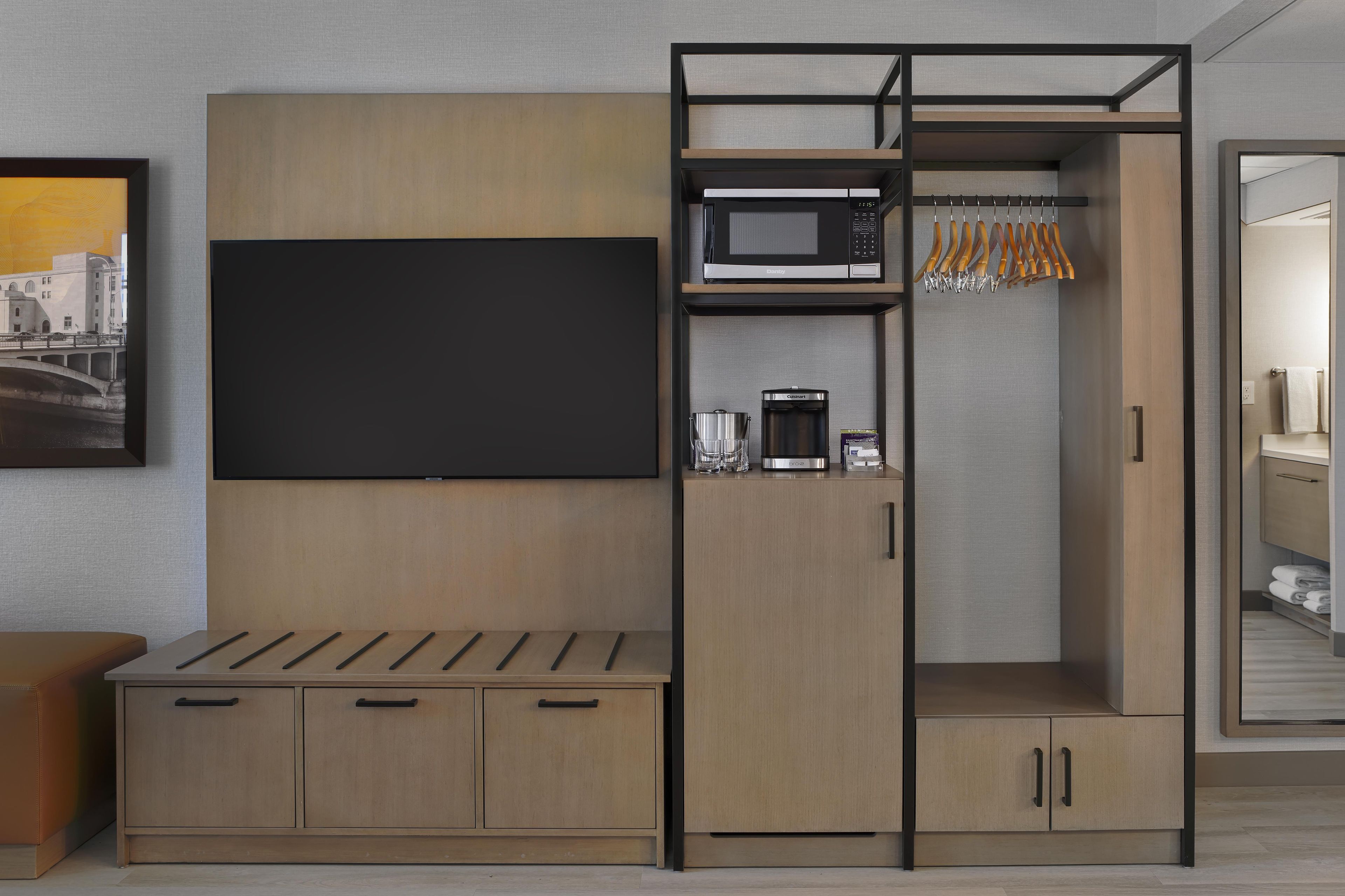 A modern kitchenette with a flat-screen TV, a microwave, and a coffee maker.