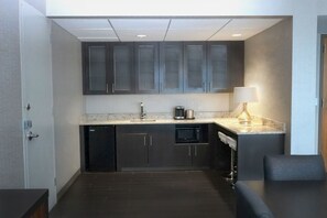 A compact kitchen with dark cabinets, a microwave, a coffee maker, and a lamp on the countertop. - Doubletree by Hilton Cedar Rapids Convention Complex (Cedar Rapids)