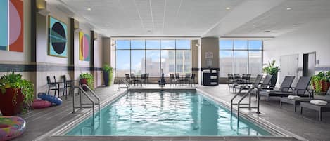 Una piscina interior con vistas al horizonte de la ciudad a través de amplias ventanas.