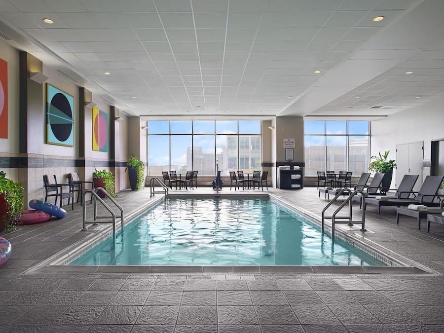 An indoor swimming pool with a view of the city skyline through large windows.