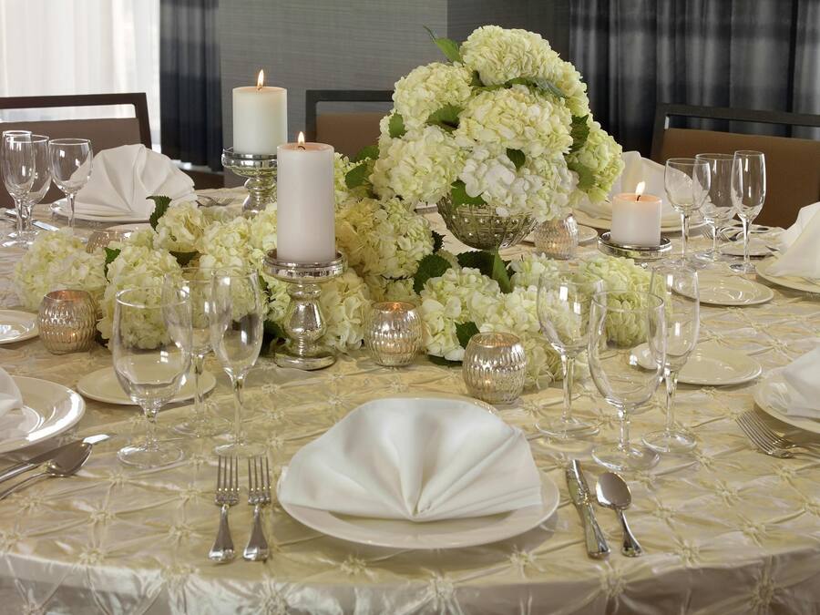 A table set for a formal event with white tablecloth, silverware, and candles.