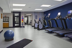 Un gimnasio con cintas de correr, elípticas y pelotas de ejercicio.