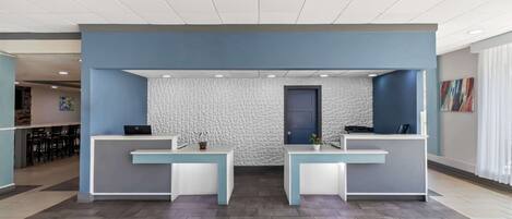 A reception area with two reception desks, a textured wall, and a door.