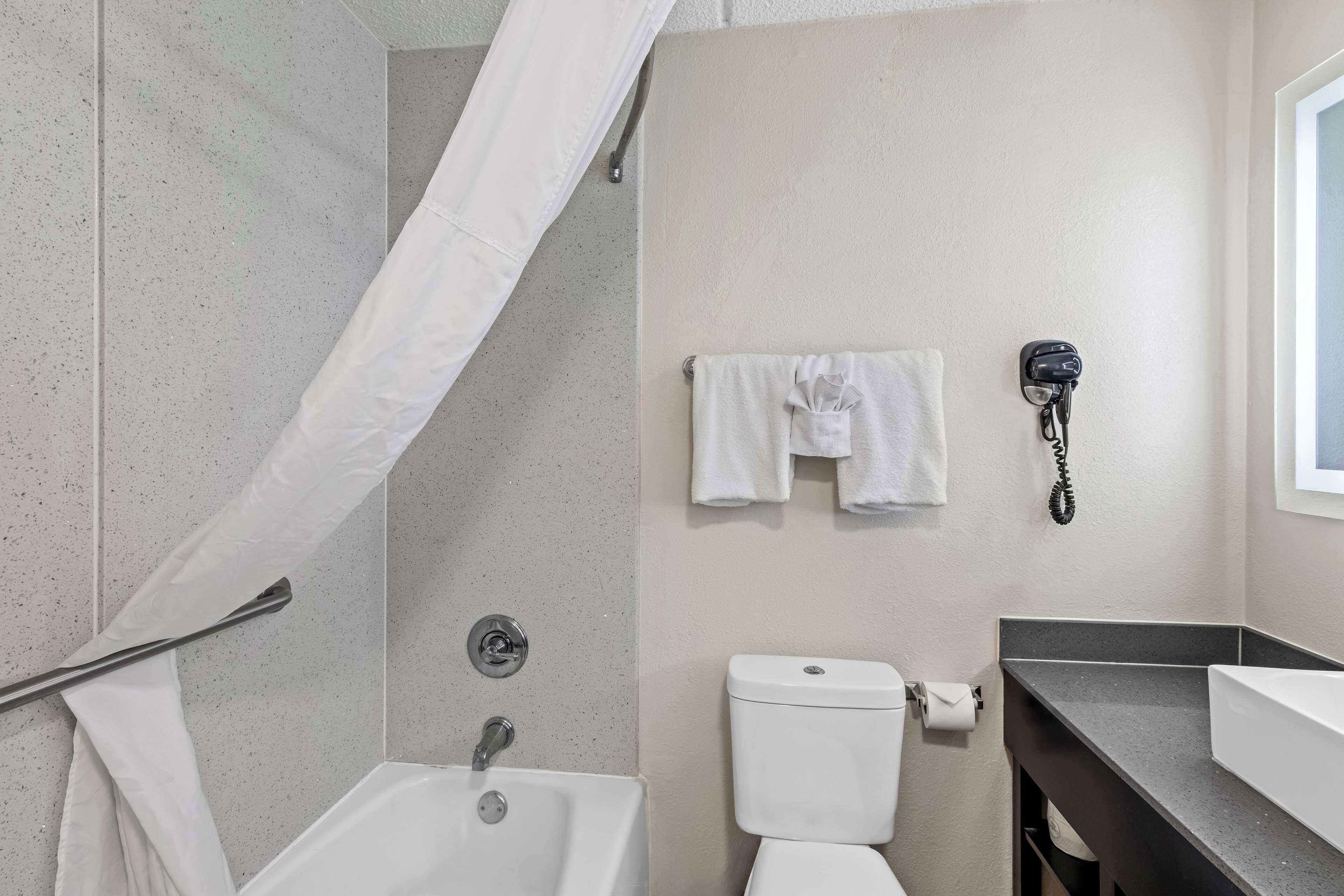 A bathroom with a shower, a toilet, a sink, and a telephone.