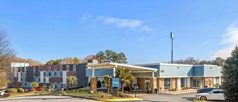 A modern building with a blue and beige facade, a parking lot, and a sign that reads "Enter."
