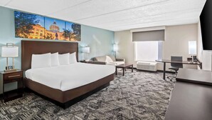 A hotel room with a large bed, a desk, a chair, a sofa, and a painting of a building on the wall. - Best Western Atlanta Cumberland/Galleria Hotel (Smyrna)