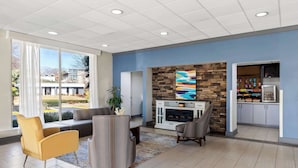 A modern interior with a seating area, a fireplace, and a kitchen area with cabinets and a television. - Best Western Atlanta Cumberland/Galleria Hotel (Smyrna)