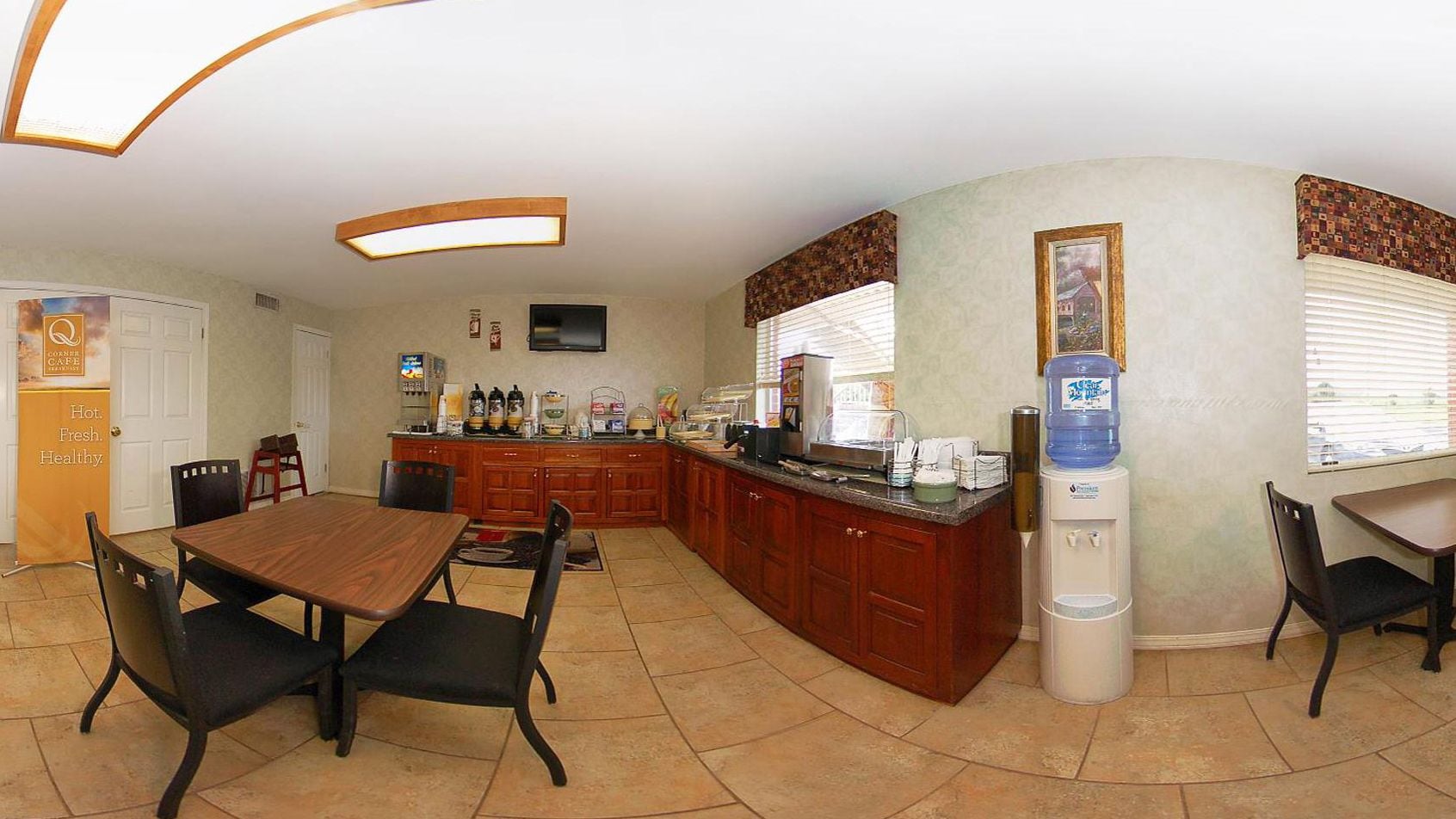 A spacious kitchen with a dining area, wooden cabinets, a water dispenser, and a coffee station.