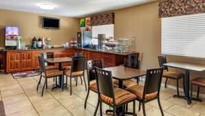 Une cuisine d’hôtel dotée de meubles en bois, d’un grand îlot central et d’un coin repas avec des chaises et des tables.