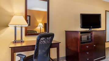 Habitación de hotel con escritorio, silla, televisión, microondas y espejo.