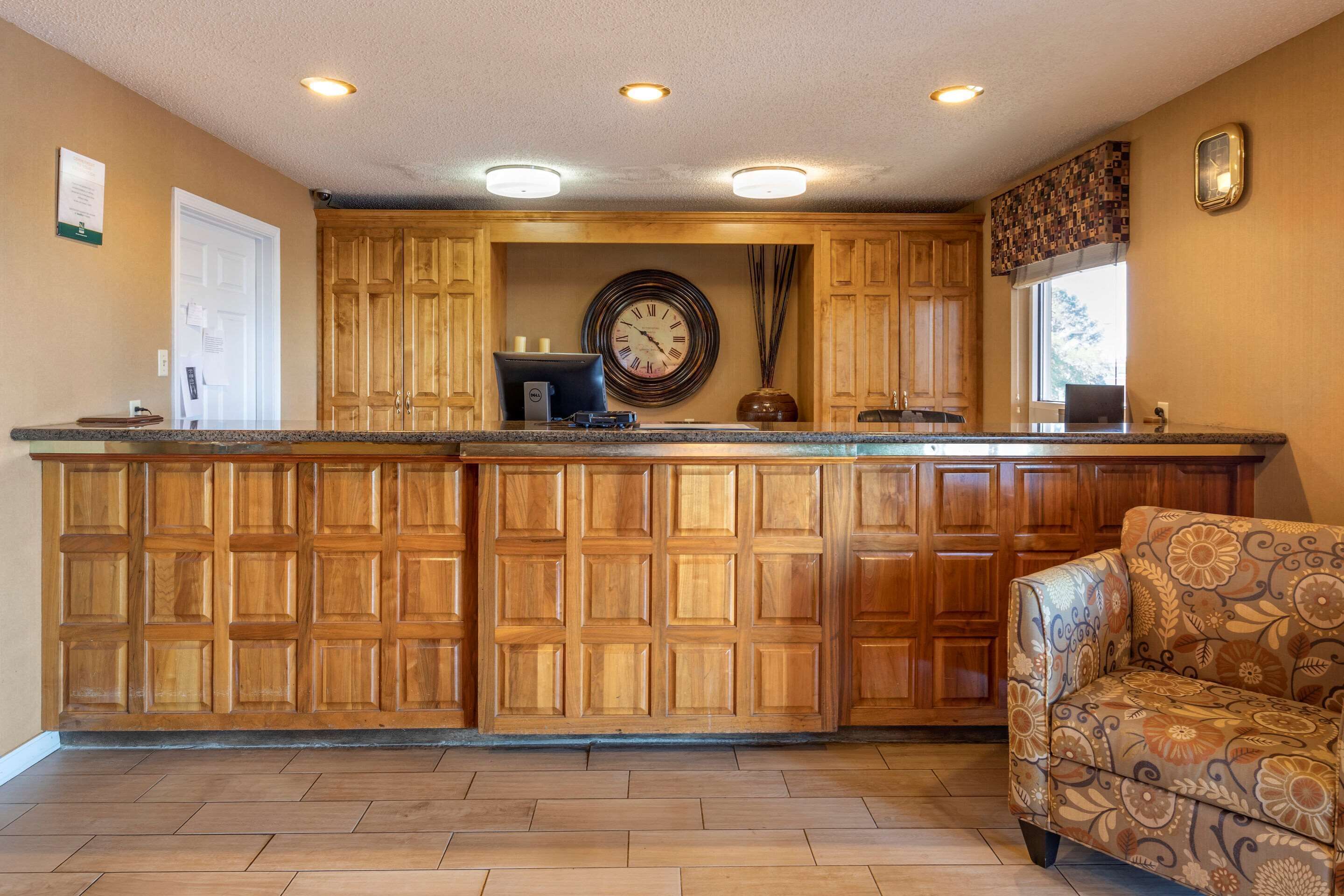 A kitchen with wooden cabinets, a built-in island, a clock, and a patterned armchair.