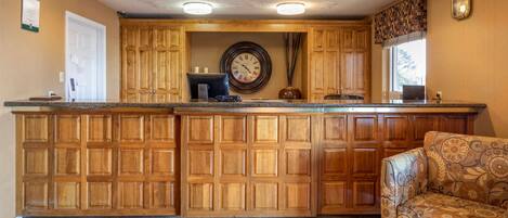 A kitchen with wooden cabinets, a built-in island, a clock, and a patterned armchair.