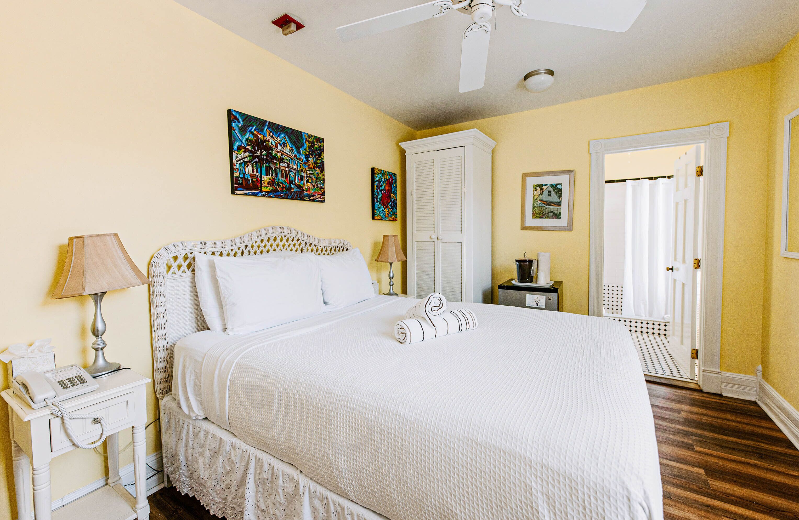 A hotel room with a bed, a nightstand with a lamp, a wardrobe, and a door leading to another room.