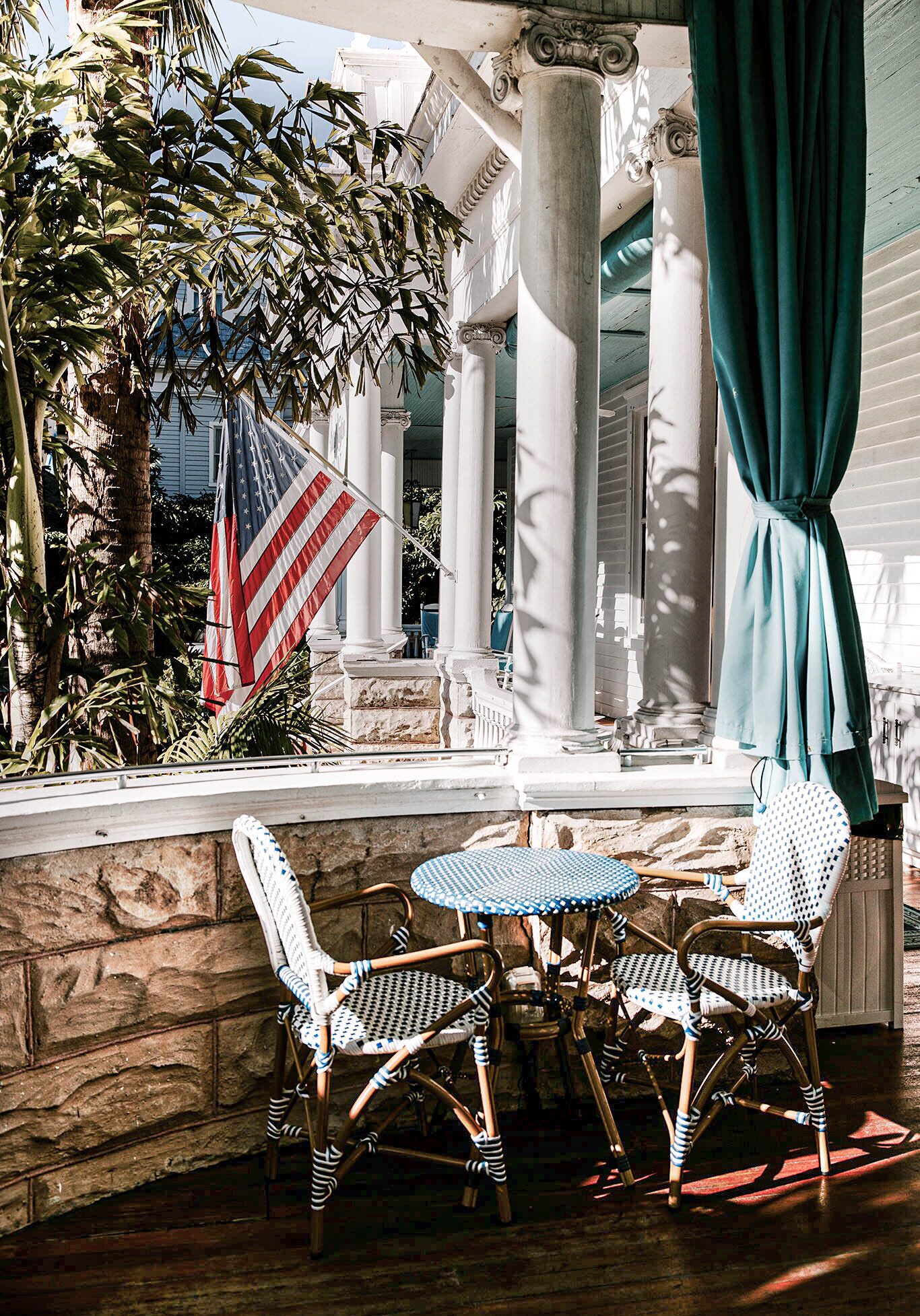 An outdoor patio with wicker chairs, a small round table, and an American flag.