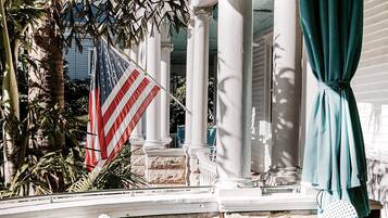 An outdoor patio with wicker chairs, a small round table, and an American flag.
