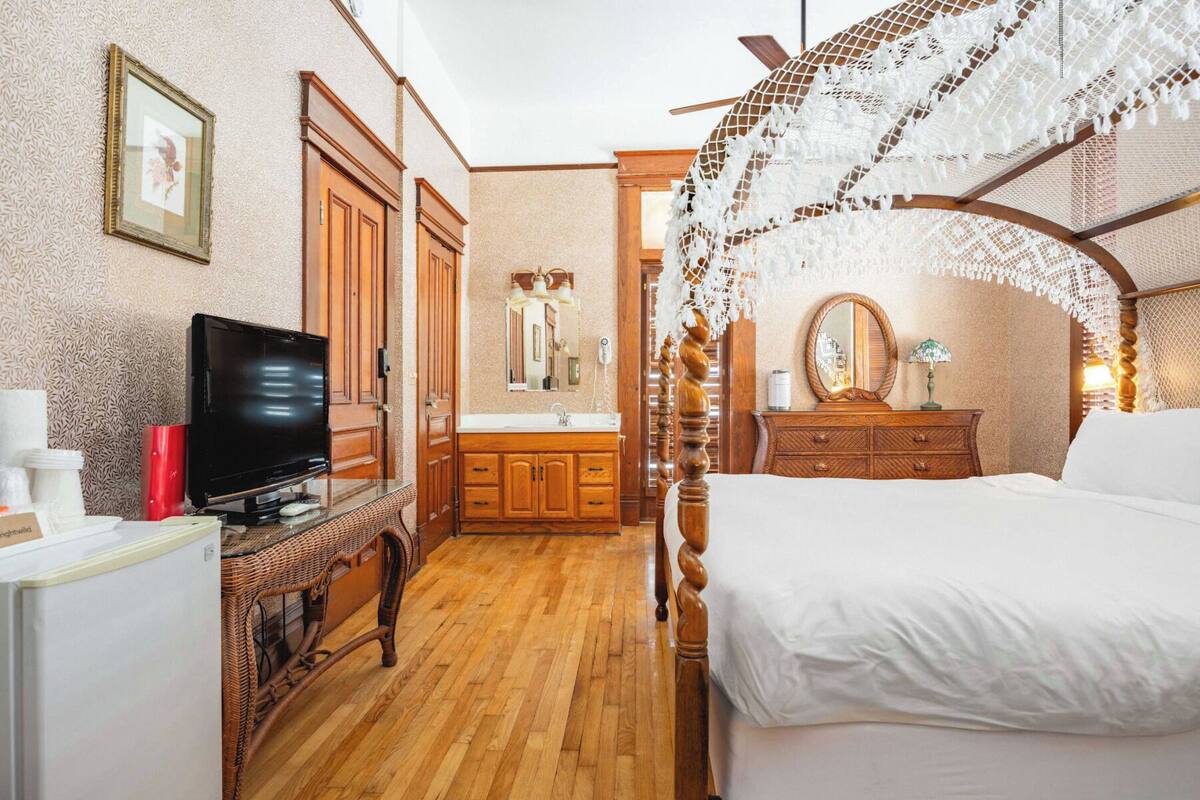 Ein Schlafzimmer mit einem Bett, einem Fernseher, Holzmöbeln und einem Spiegel.