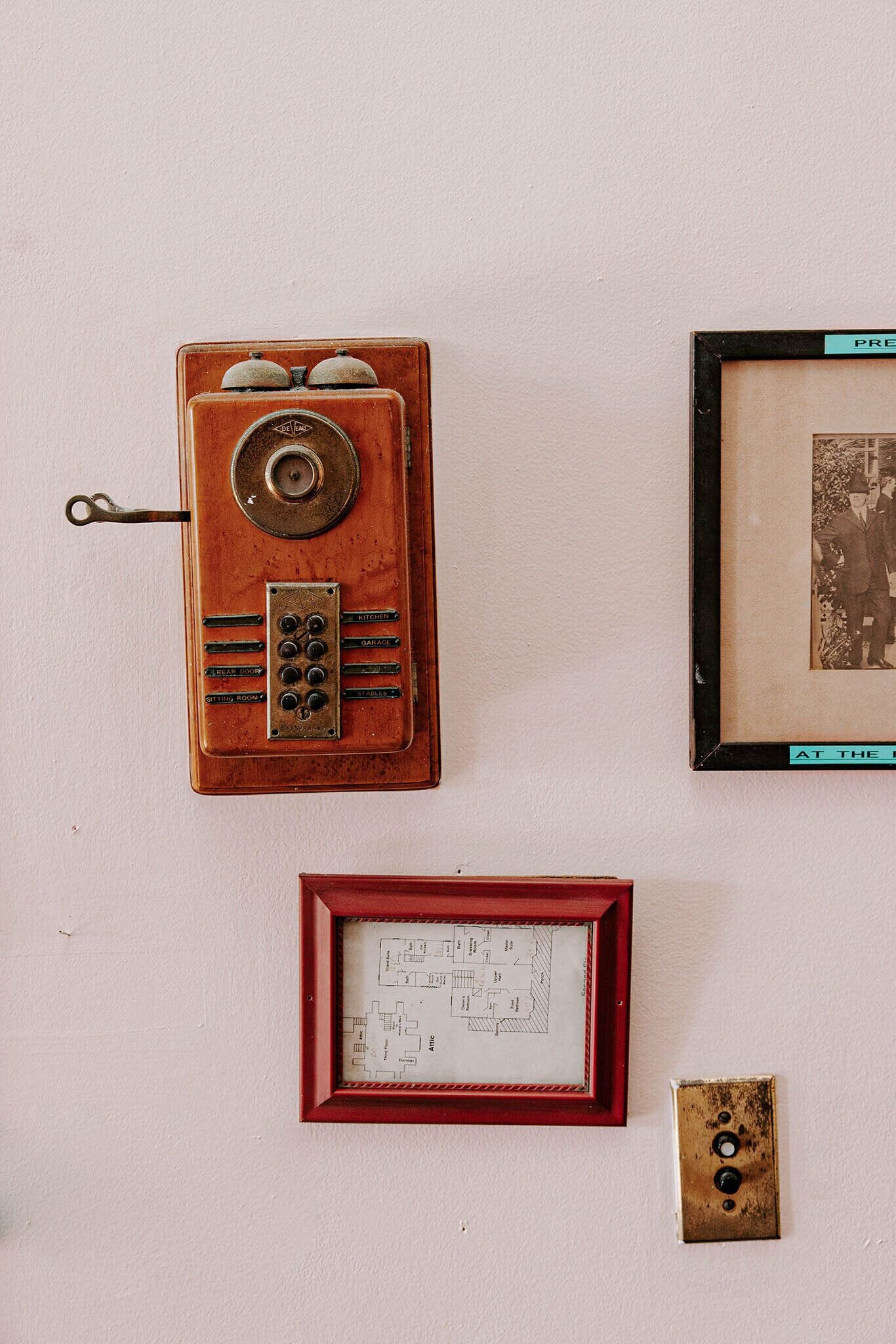 Um rádio antigo, uma fotografia emoldurada e um projeto arquitetônico emoldurado em uma parede.