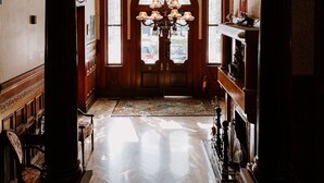 A grand hallway with ornate ironwork, a chandelier, and a wooden floor. - Amsterdam's Curry Mansion Inn (Key West)