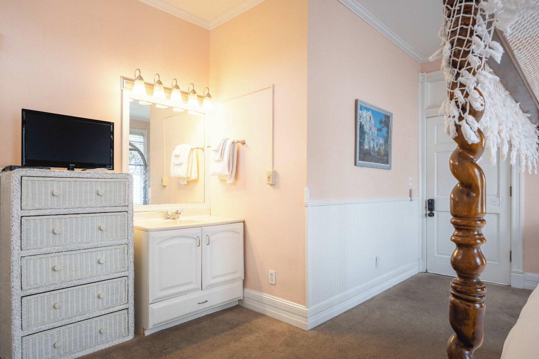 A bathroom with a vanity, mirror, and a television on a dresser.