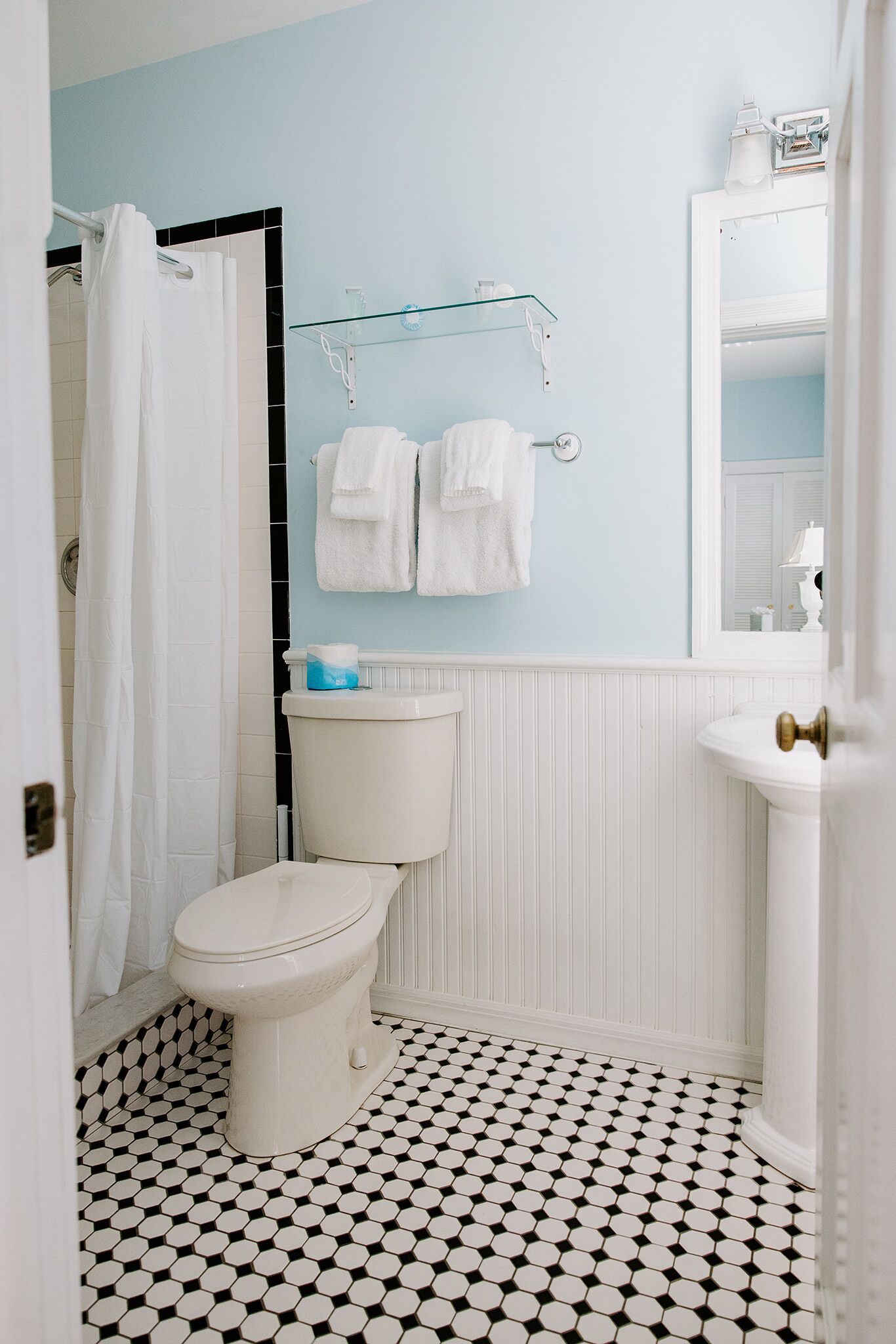 Un baño con inodoro, ducha, lavabo y espejo.