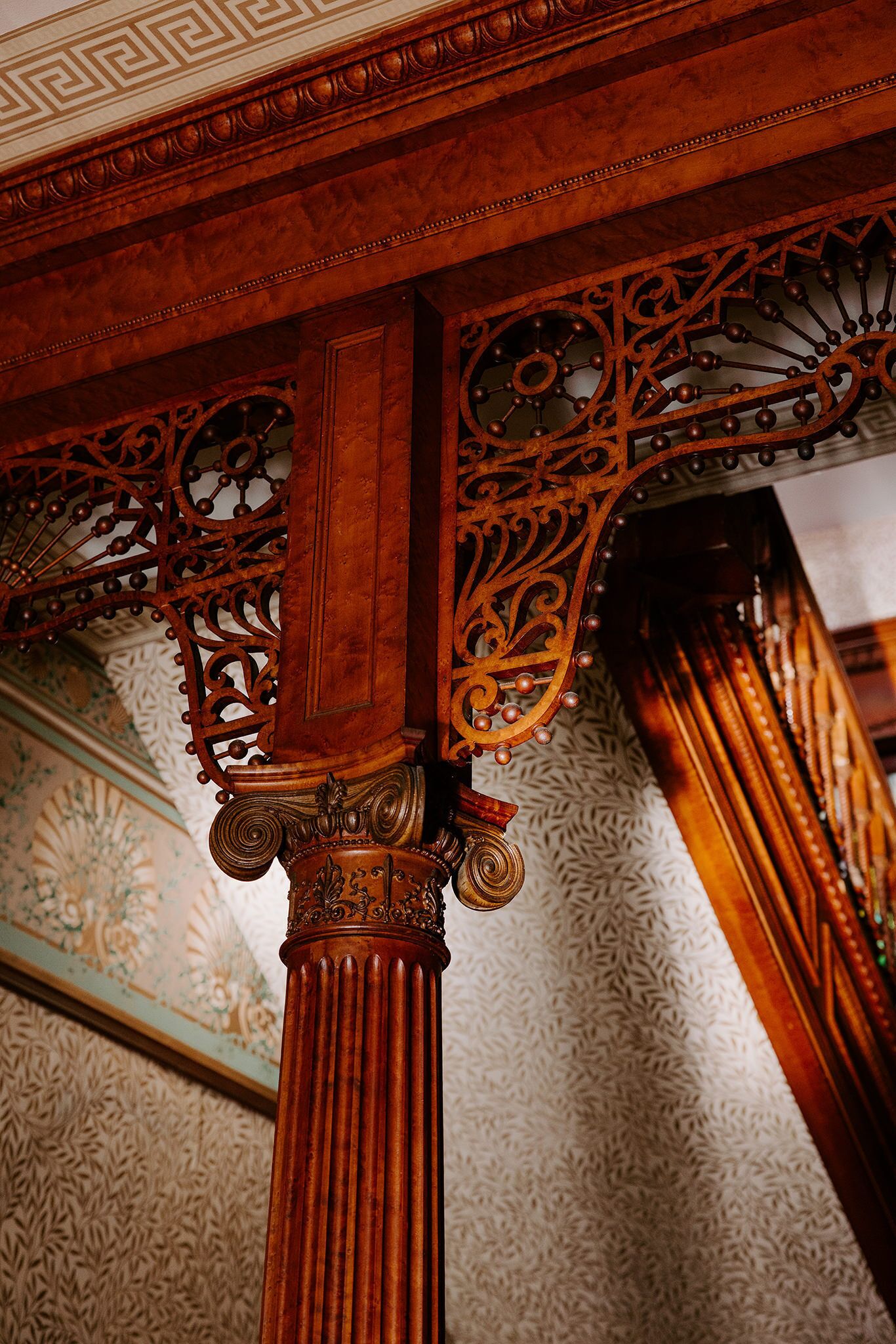 A detailed view of a wooden column with intricate carvings and a patterned ceiling.