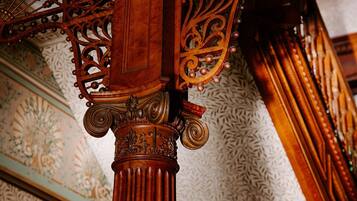 A detailed view of a wooden column with intricate carvings and a patterned ceiling.