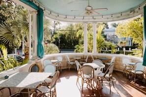 A covered patio area with wicker furniture and a ceiling fan.